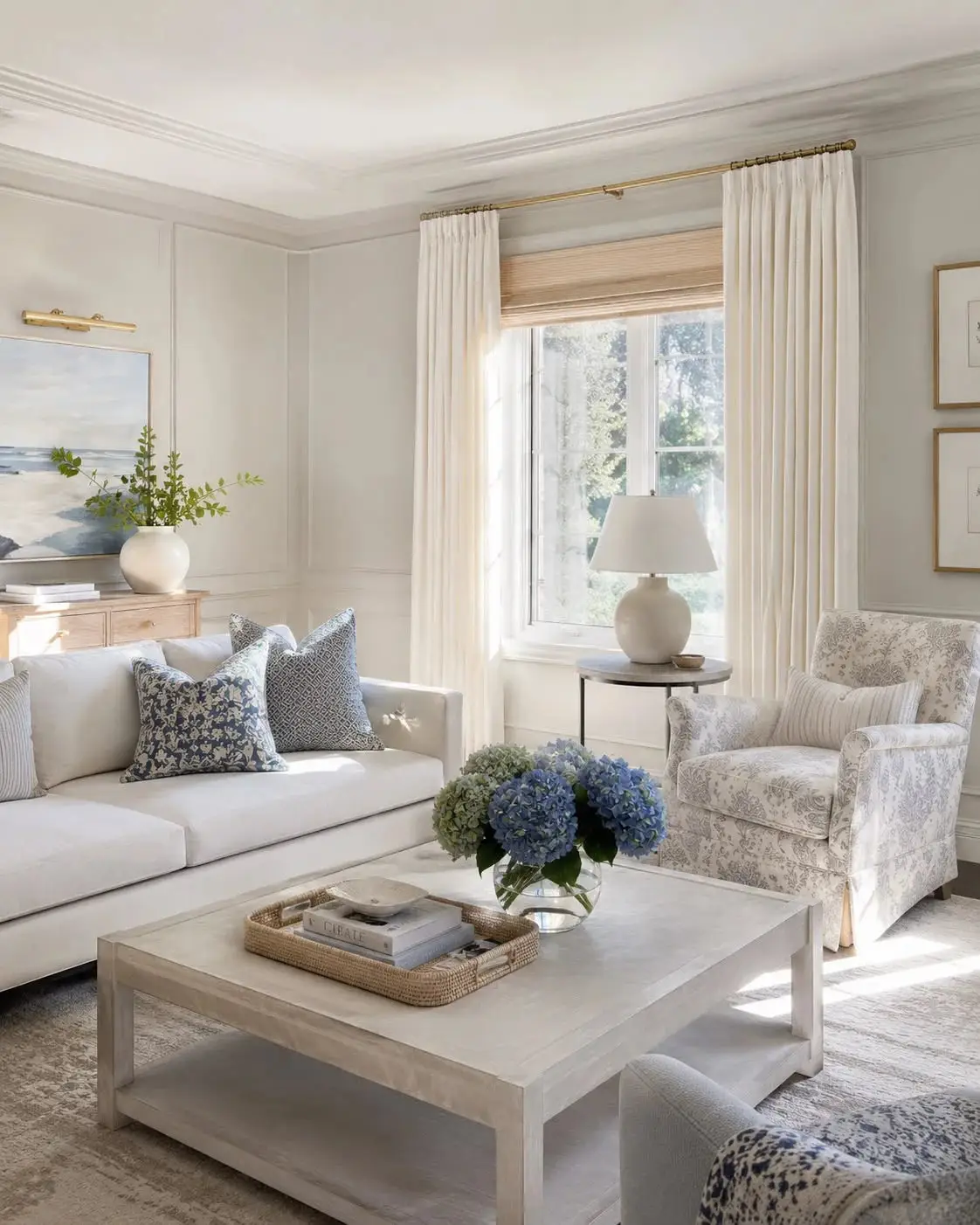 Elegant living room with cream sofa, blue floral pillows, and hydrangeas on wooden coffee table