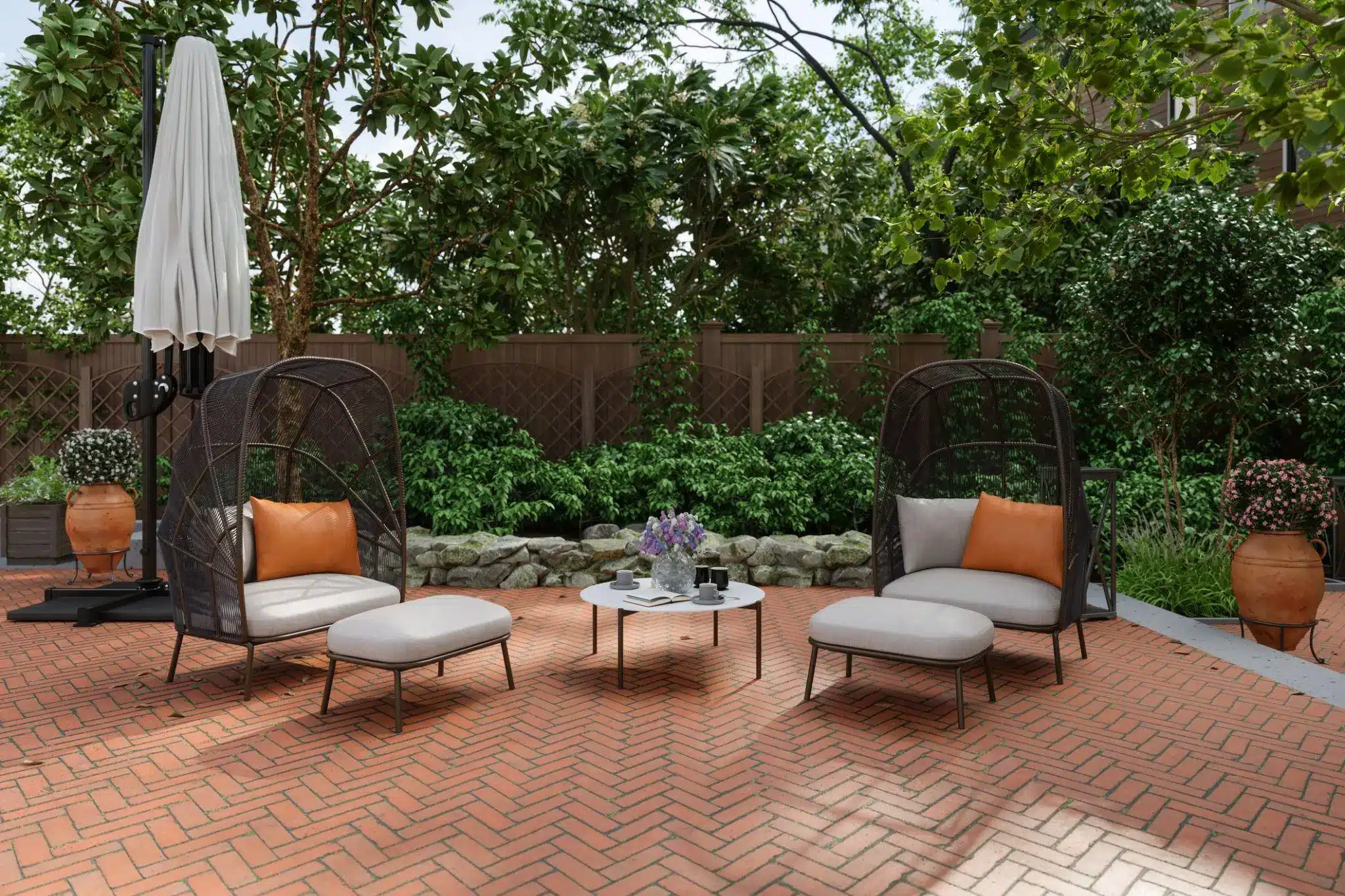 Wicker patio chairs with orange cushions on brick terrace surrounded by greenery and trees