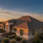 Single-story house with stone accents in arid landscape at sunset, surrounded by desert plants