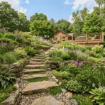 lush hillside garden with stone steps colorful flowers and layered landscaping leading to wooden deck and house