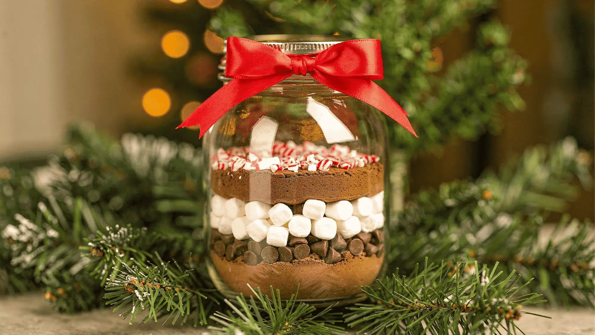 mason jar layered with cocoa, marshmallows, and chocolate, candy cane tied with ribbon (1)