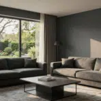 modern living room with two charcoal sofas a dark coffee table and a large window overlooking a lush green garden