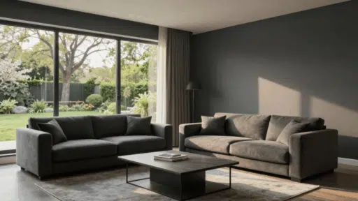 modern living room with two charcoal sofas a dark coffee table and a large window overlooking a lush green garden