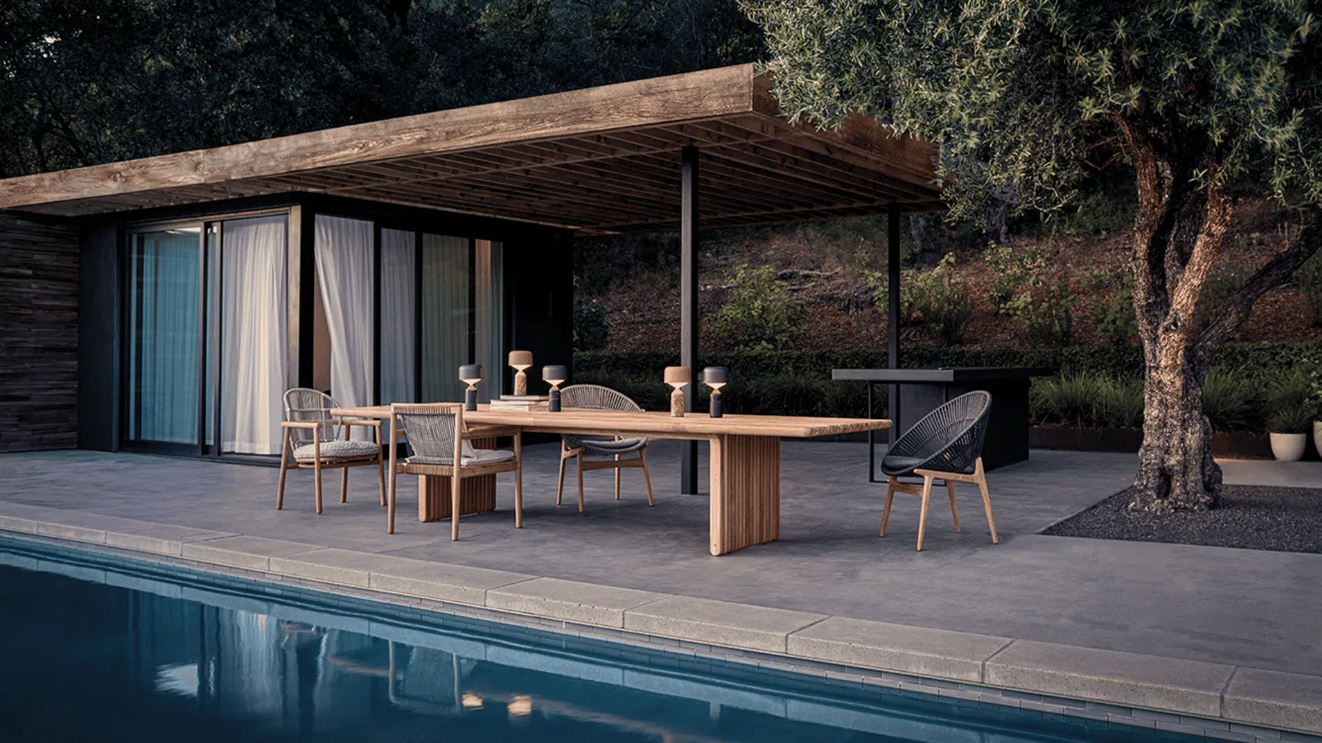 modern outdoor dining table with woven chairs beside pool under covered patio surrounded by trees