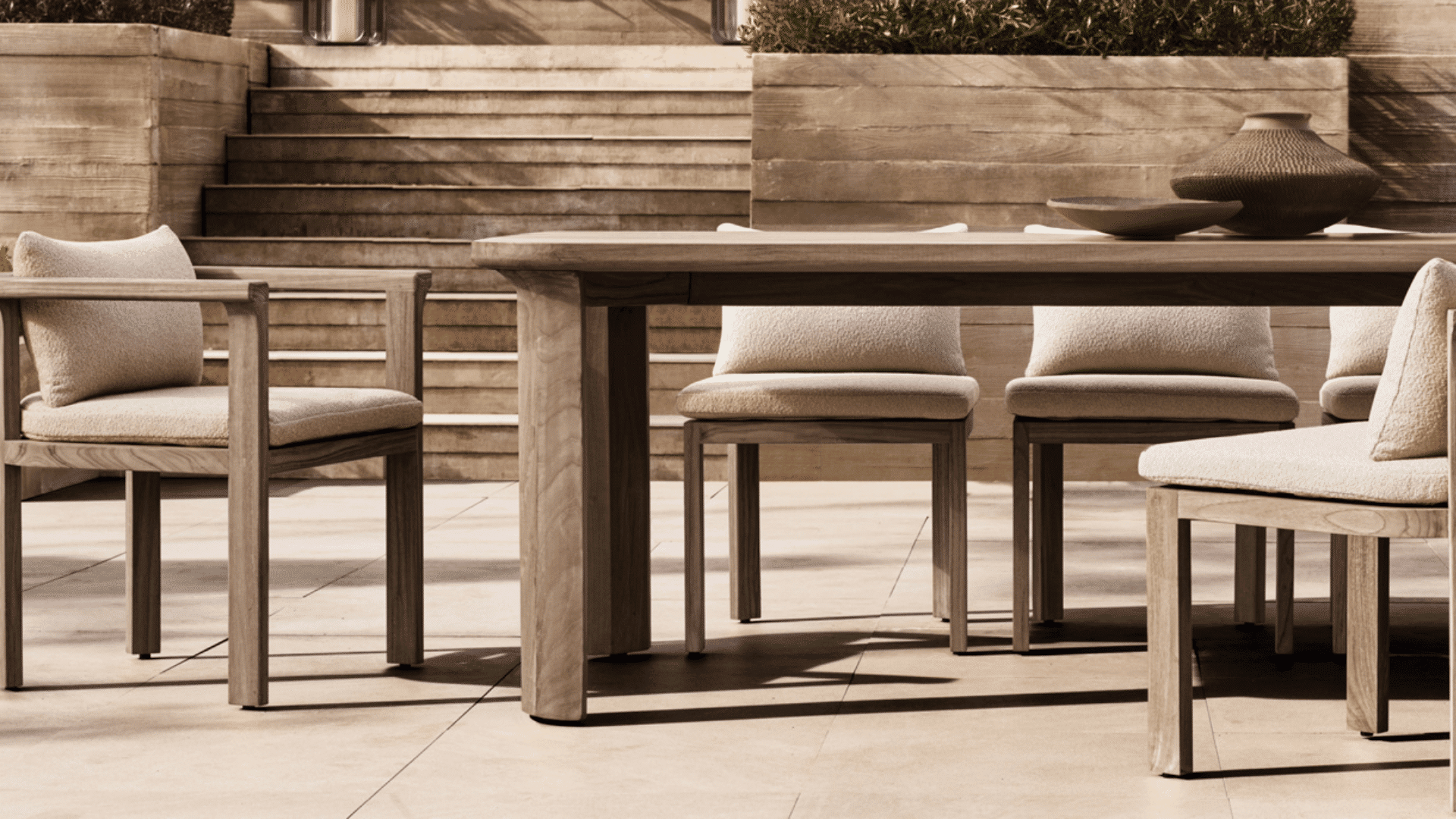 modern wooden outdoor dining set with cushioned chairs arranged on elegant stone terrace patio