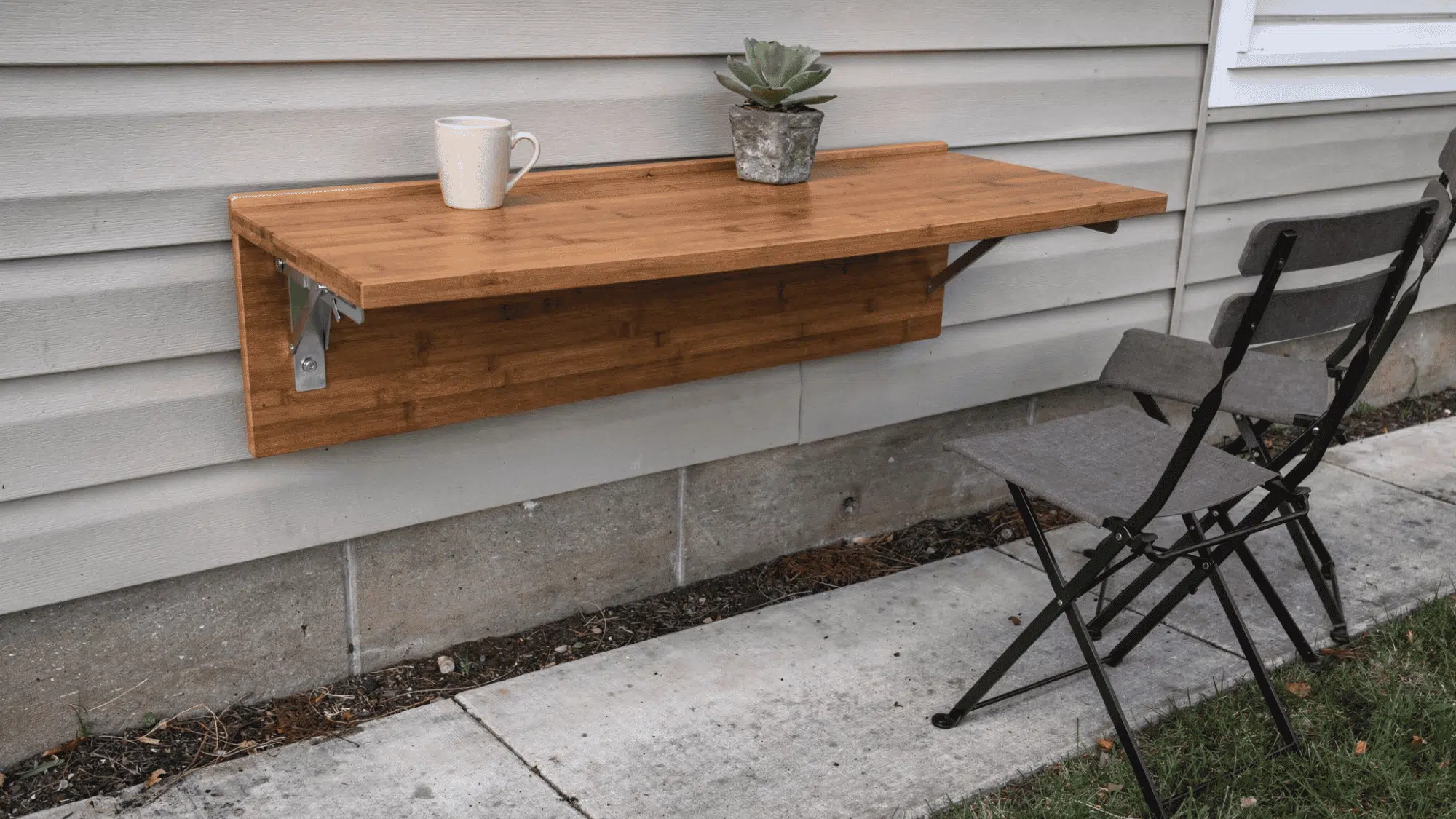 narrow suburban porch with a wall mounted folding wooden table holding a coffee mug and slim chairs nearby