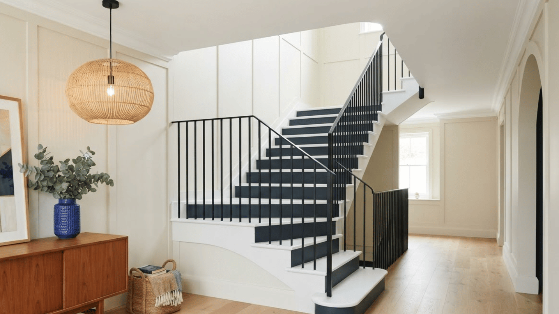 navy painted stair risers with natural oak treads and white trim in a bright entryway
