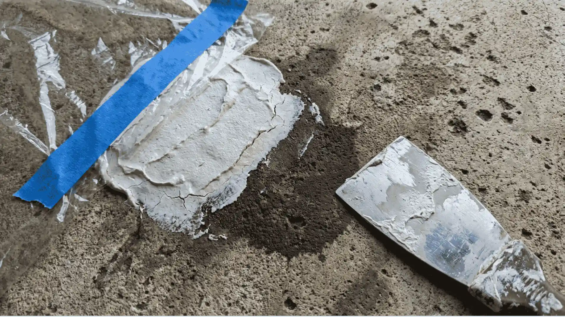 thick gray poultice paste spread over a deep set oil stain on aged concrete surface