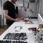 optician adjusting a pair of glasses at a professional workbench surrounded by multiple frames and eyewear tools in a well lit practice