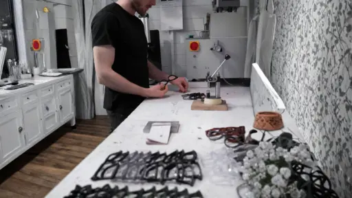 optician adjusting a pair of glasses at a professional workbench surrounded by multiple frames and eyewear tools in a well lit practice