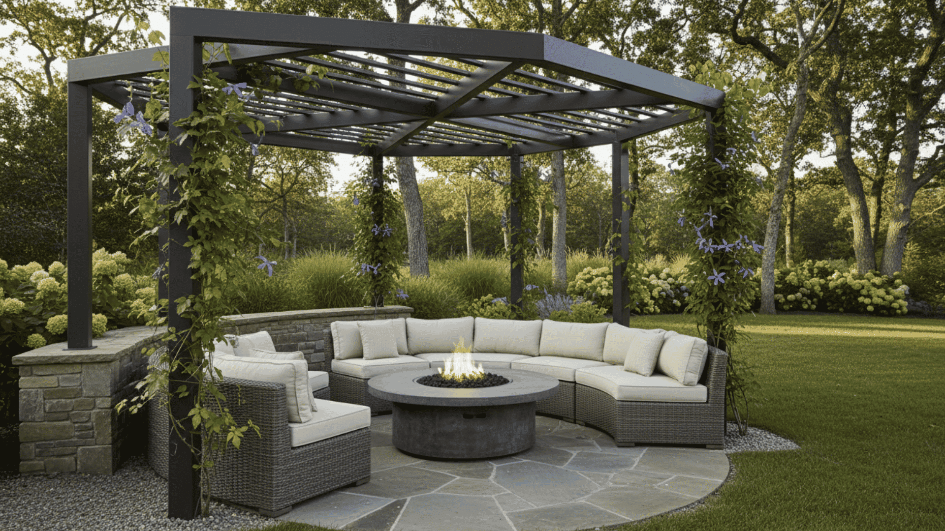 Outdoor sectional lounge under a pergola with a central fire pit and surrounding greenery.