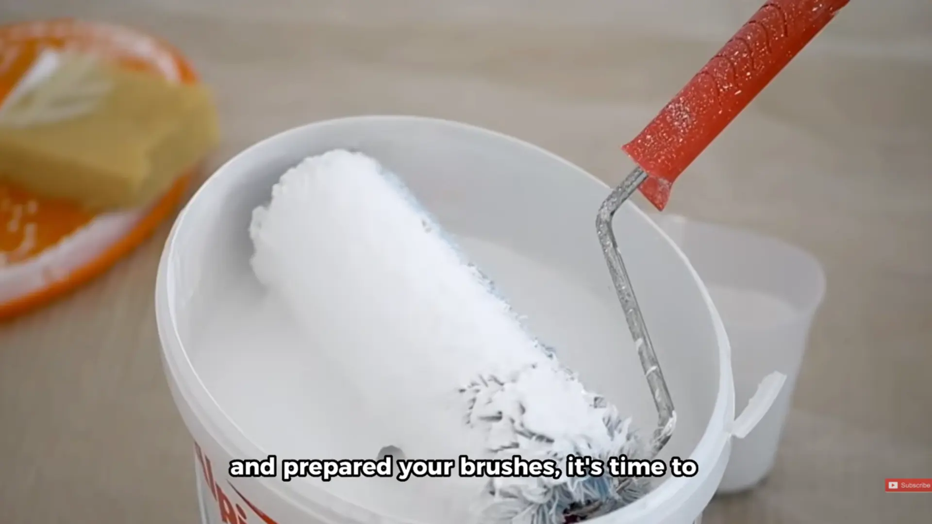 paint roller dipped into a bucket of white paint before coating a garage door surface