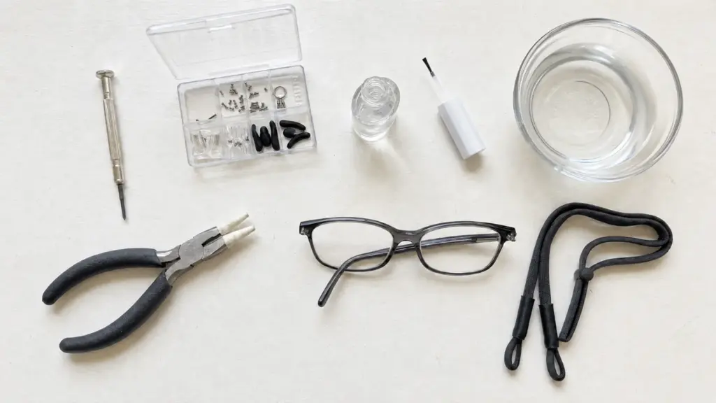 precision screwdriver, eyeglass repair kit, clear nail polish, needle-nose pliers and a pair of loose glasses laid out on white desk