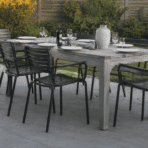 realistic outdoor dining table setup with black chairs on modern patio surrounded by green backyard garden