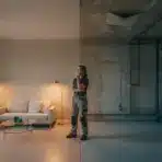 Person contemplating in room with modern furniture and exposed unfinished wall in warm lighting