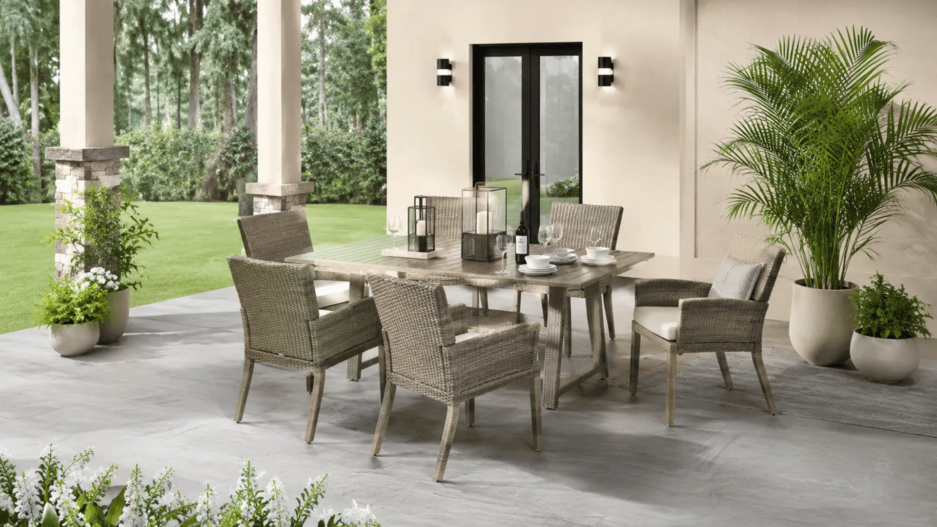 small outdoor patio dining set with cushioned chairs and table arranged beside modern home entrance
