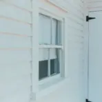 White wooden siding with a single-pane window and door in natural daylight