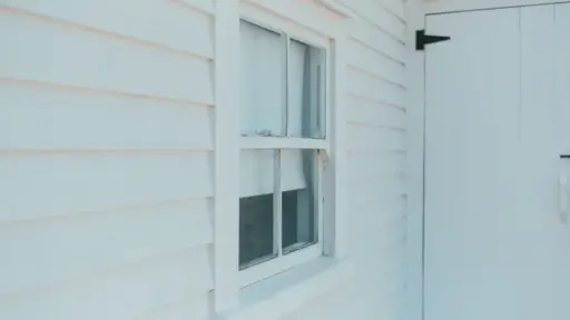 White wooden siding with a single-pane window and door in natural daylight