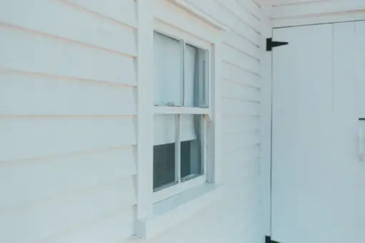 White wooden siding with a single-pane window and door in natural daylight