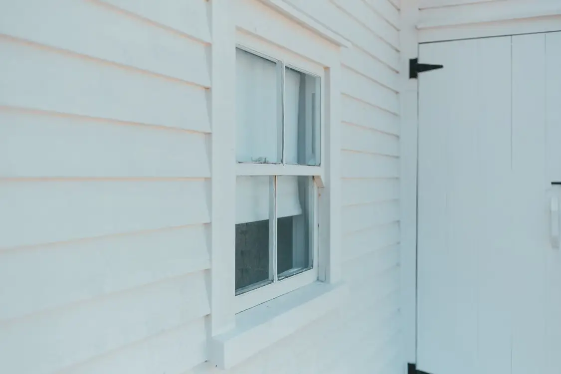 White wooden siding with a single-pane window and door in natural daylight