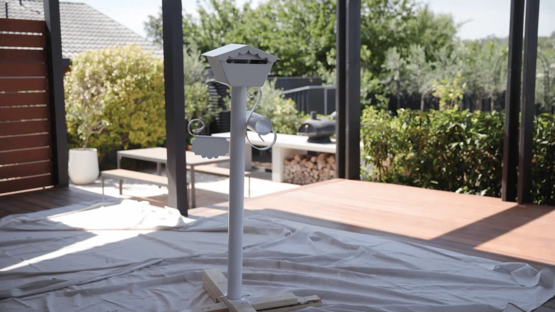 freshly painted metal mailbox post drying on a drop cloth after the final coat of white paint has been applied