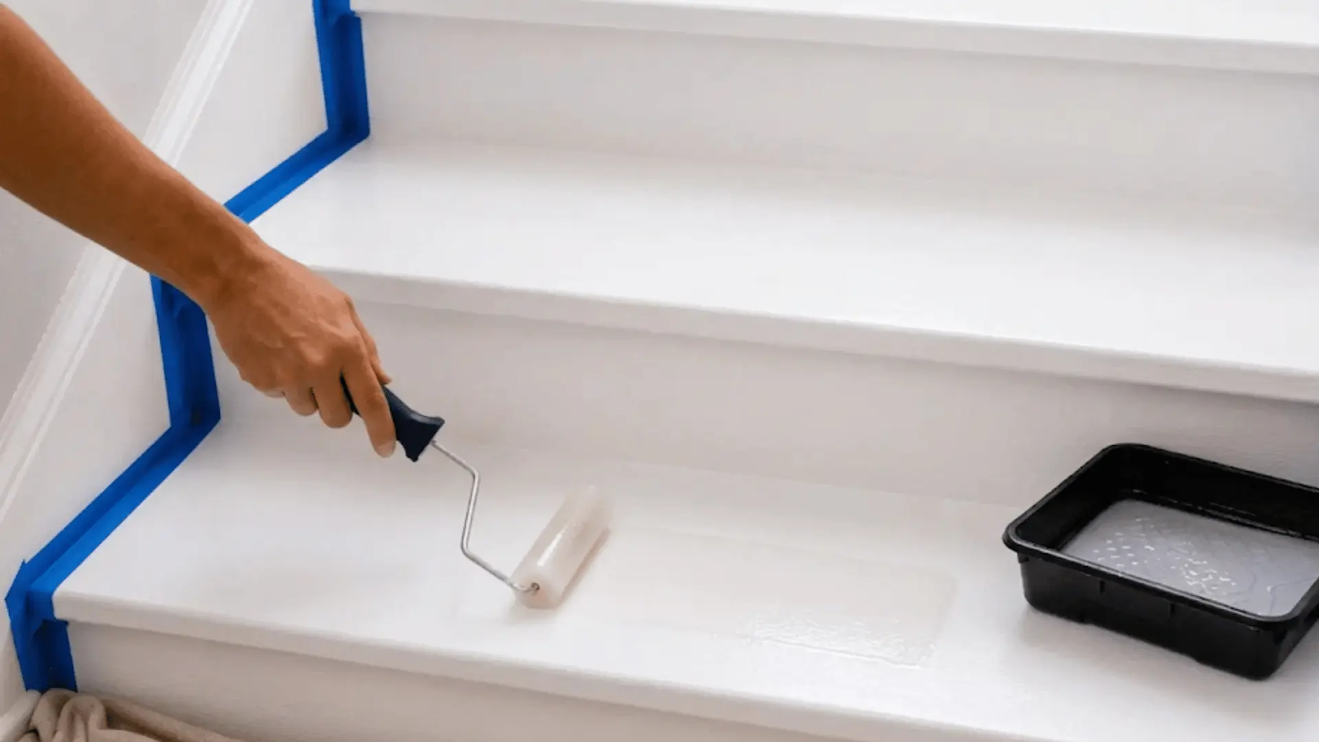 hand applying clear protective sealer over freshly painted white stairs with a small roller