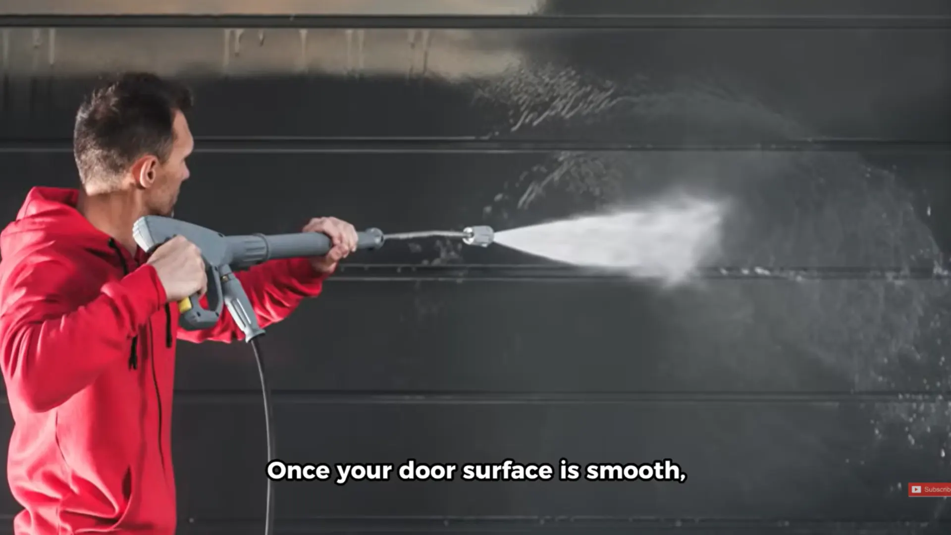 man pressure washing a dark garage door to clean the surface before painting and smooth the finish