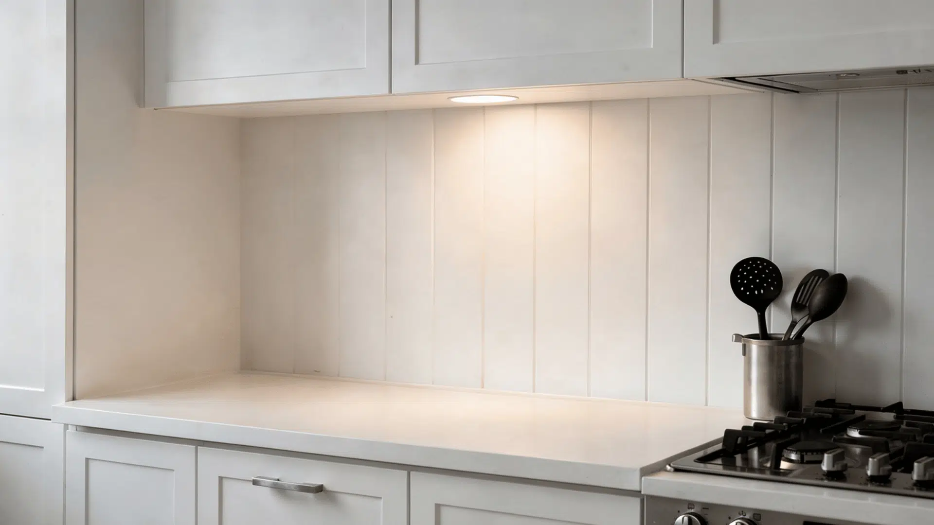 white beadboard textured accent wall behind a kitchen island with soft pendant light casting groove shadows