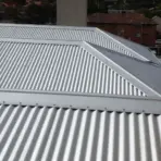 Corrugated metal roofing on residential building under overcast sky