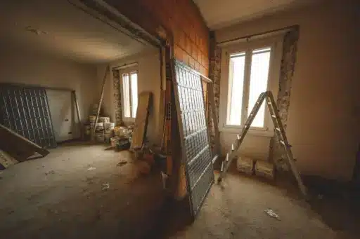 Renovation scene with ladder and construction materials in partially finished room with exposed brick walls