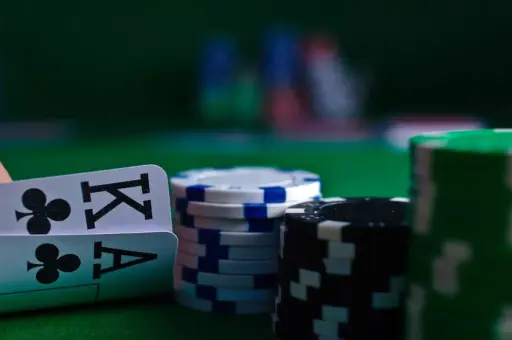 Poker chips and playing cards on green felt table in dimly lit casino setting