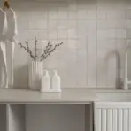 White t-shirts hanging in modern laundry room with tiled backsplash and countertop accessories