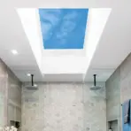 Modern bathroom with skylight, hexagonal tiles, dual rain showerheads, and gray walls