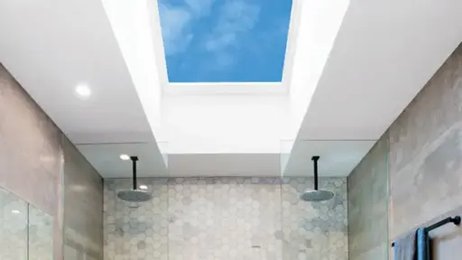 Modern bathroom with skylight, hexagonal tiles, dual rain showerheads, and gray walls