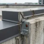 Concrete parapet with rusted metal railing on rooftop, under cloudy sky