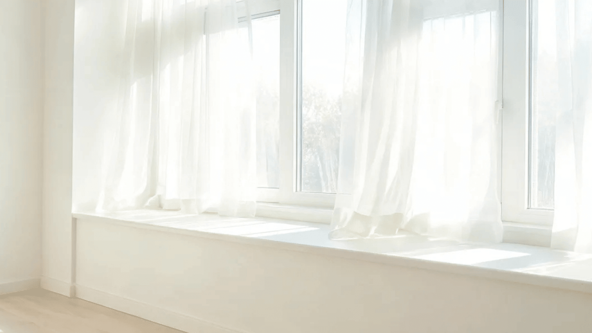 window nook with white cushions and sunlight coming through sheer curtains