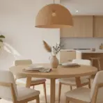 Round wooden dining table with plates and vase in modern kitchen with pendant light