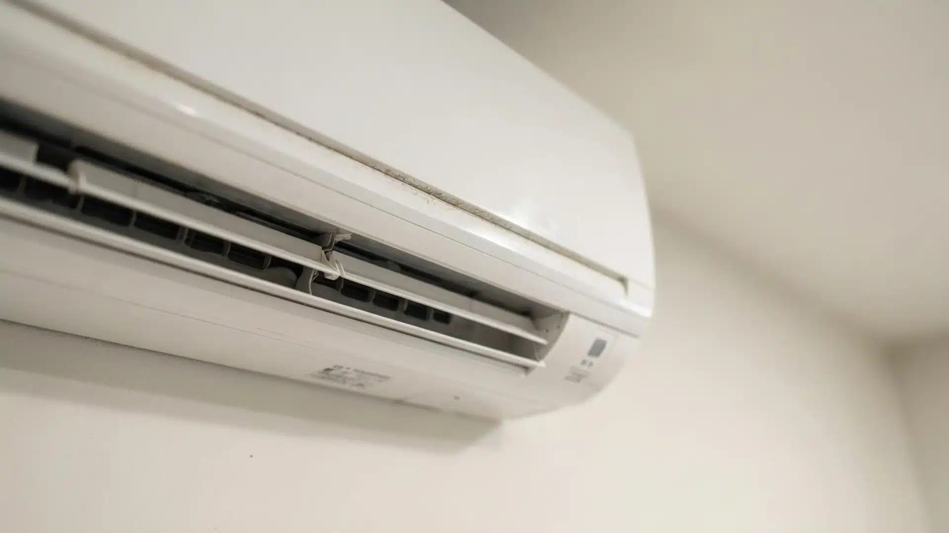 indoor split ac unit mounted on wall with visible dust and grime buildup along the front vent panel