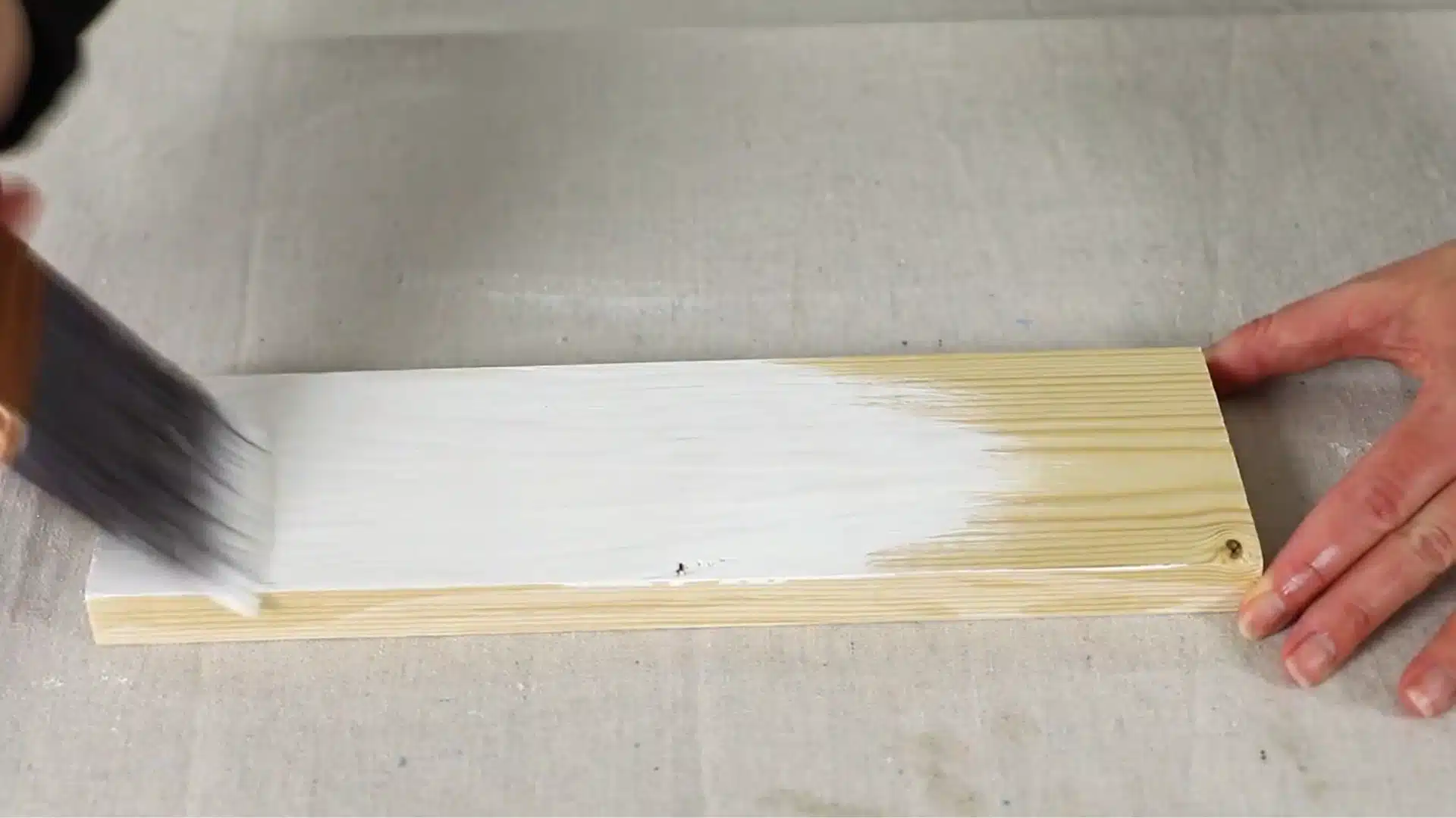 brushing white wash mixture onto bare pine wood plank