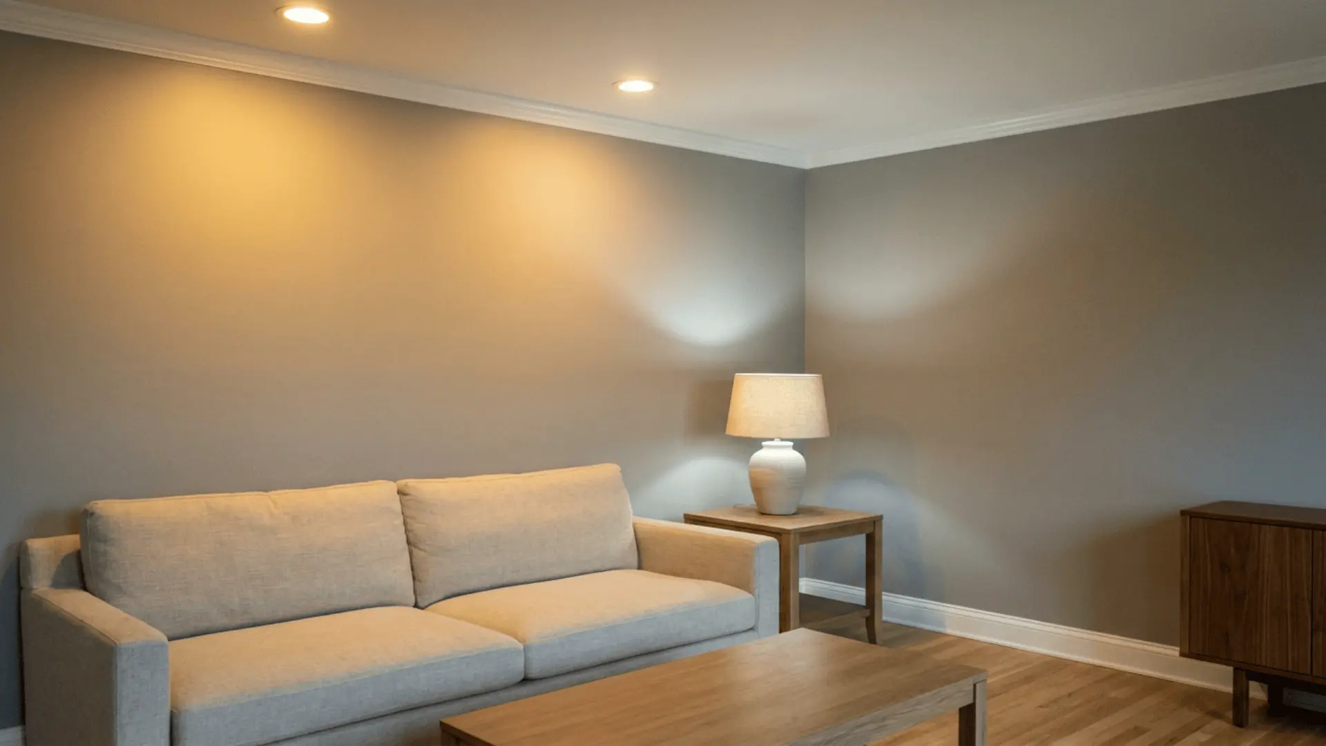 gray living room with cream sofa wooden coffee table side lamp hardwood floor recessed lights and small cabinet