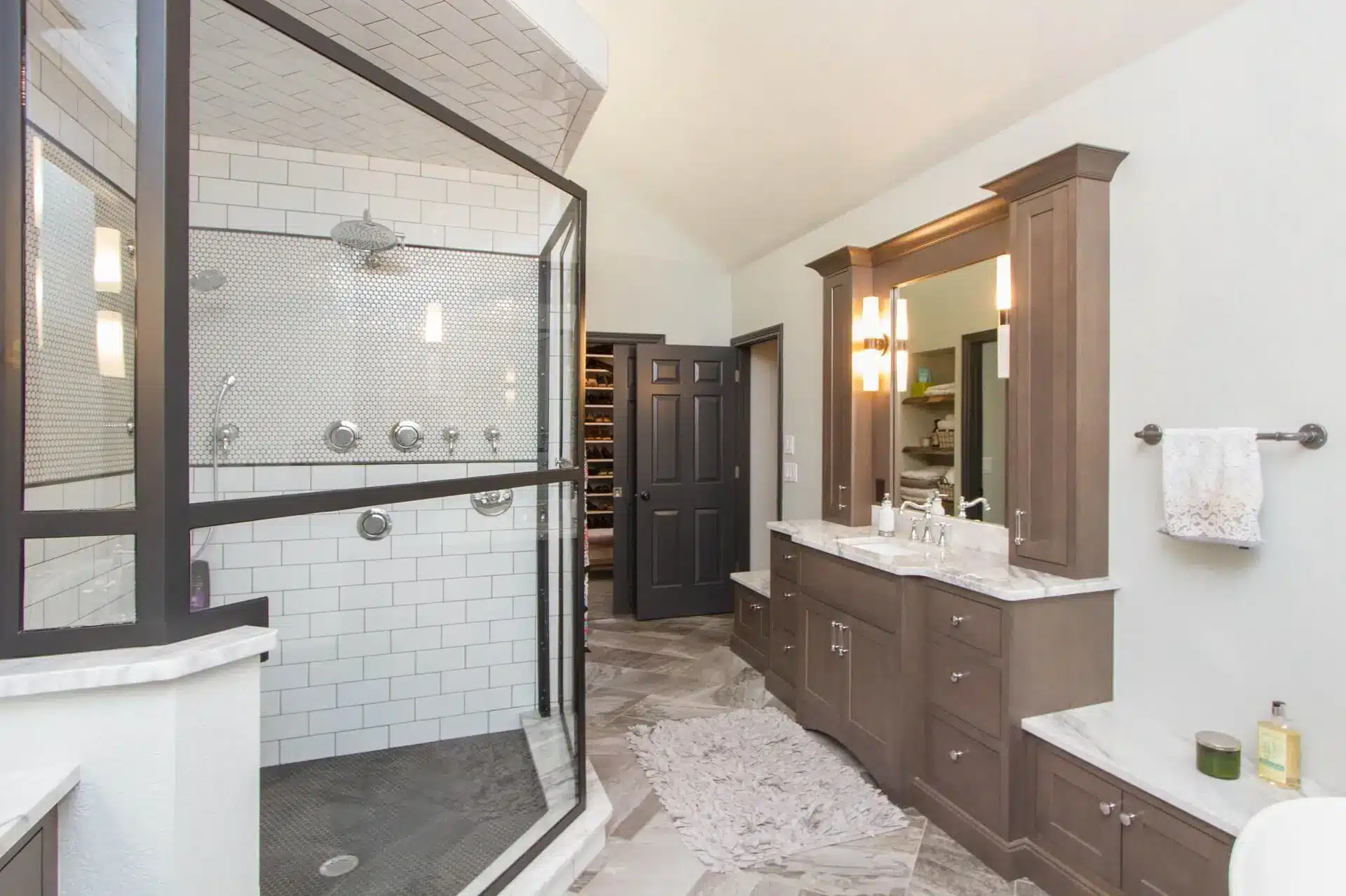 Modern bathroom with glass shower enclosure, dark wood vanity, and white tile walls
