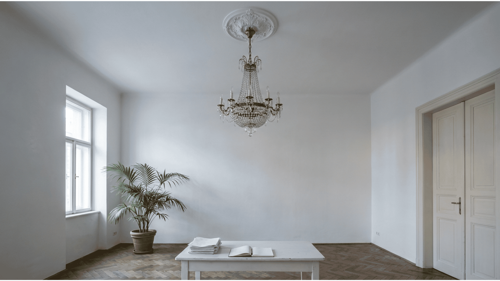 bright white period room with a crystal chandelier hanging from the ceiling above a white table