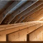 parallel wooden ceiling joists and sloping roof rafters seen from below in an unfinished attic space
