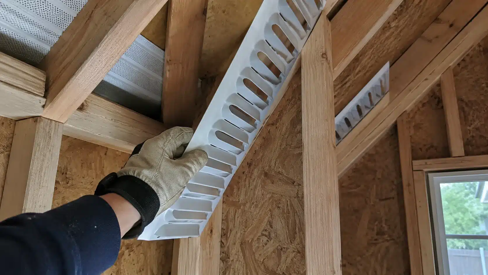 installing a roof ventilation baffle between shed rafters before adding insulation