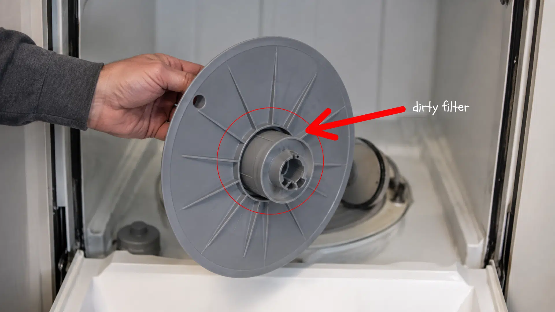 hand removing a dishwasher filter assembly from the lower basin to clear trapped food and debris