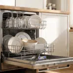 open dishwasher filled with dirty plates and cloudy glasses in a bright modern kitchen