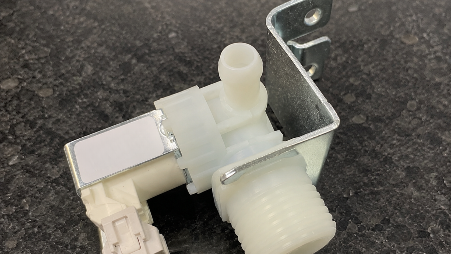 faulty dishwasher water inlet valve resting on a light kitchen countertop for inspection