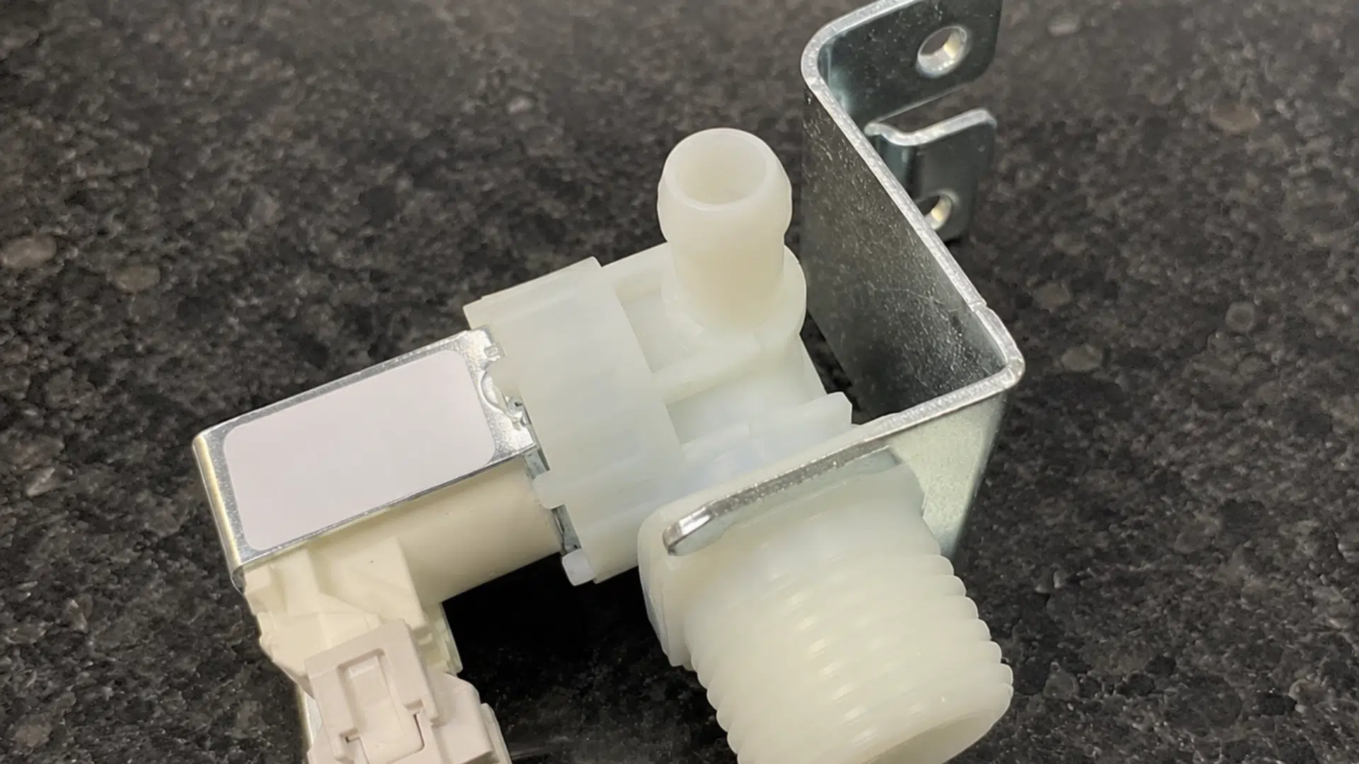 faulty dishwasher water inlet valve resting on a light kitchen countertop for inspection