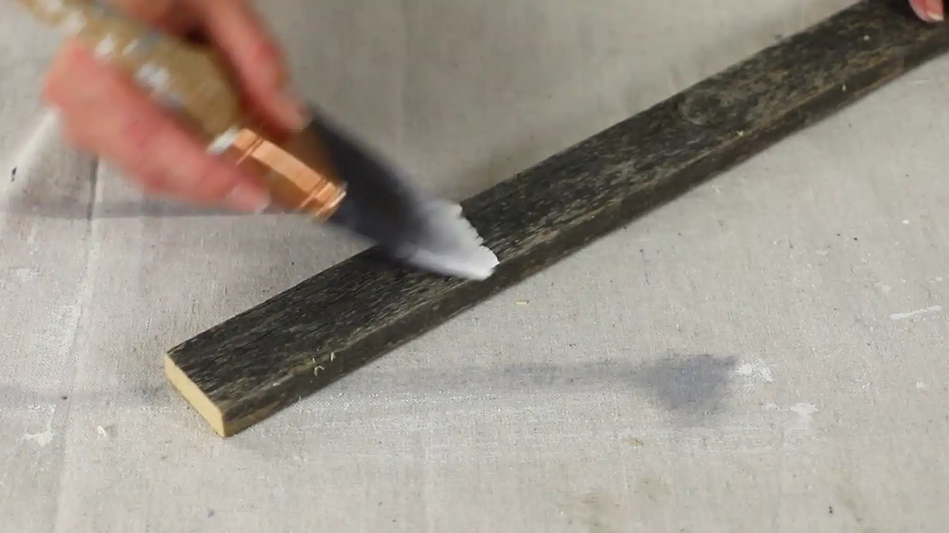 applying second coat of white wash to weathered wood plank