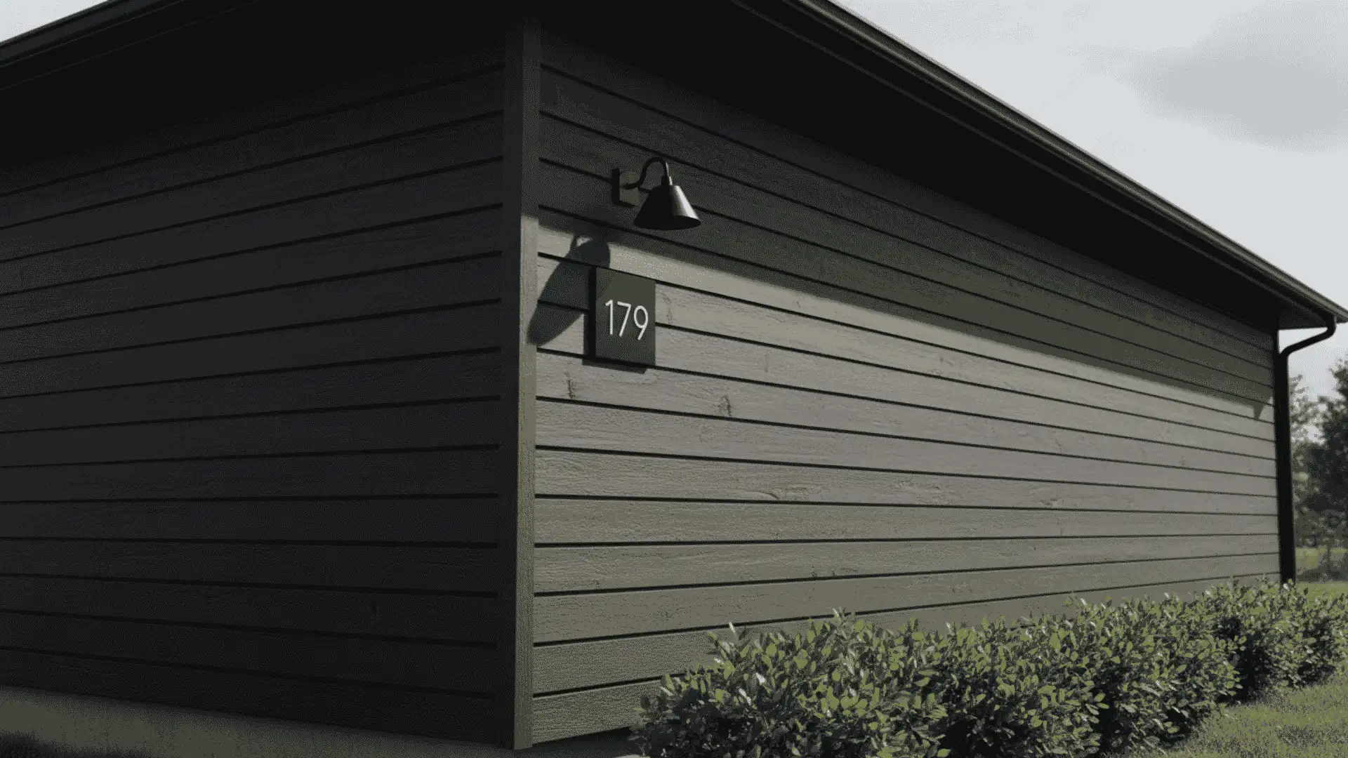dark shiplap exterior siding on a modern building with wall light house number and shrubs